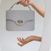 a woman's hand holding a gray purse