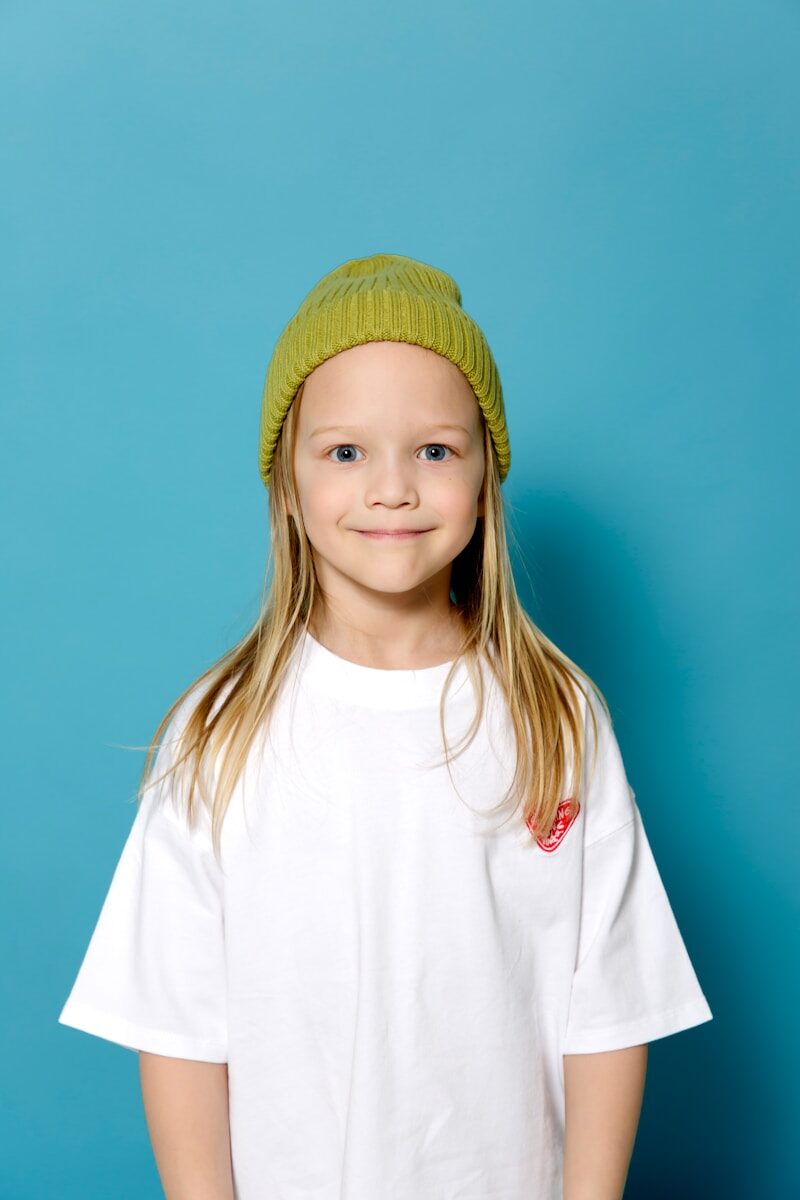 a young girl wearing a white shirt and a green hat